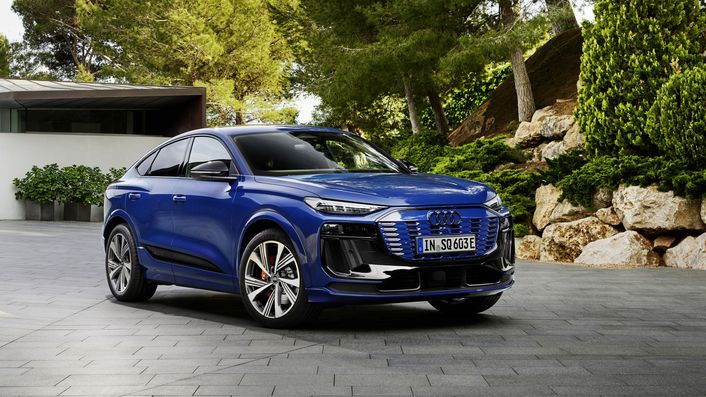 Ein blau lackierter Audi SQ6 Sportback e-tron auf einer Auffahrt vor Bäumen