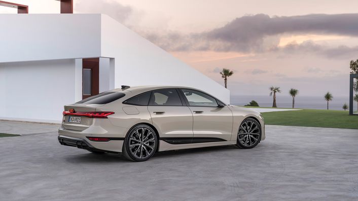 A beige Audi A6 Sportback e-tron in front of a house at sunset