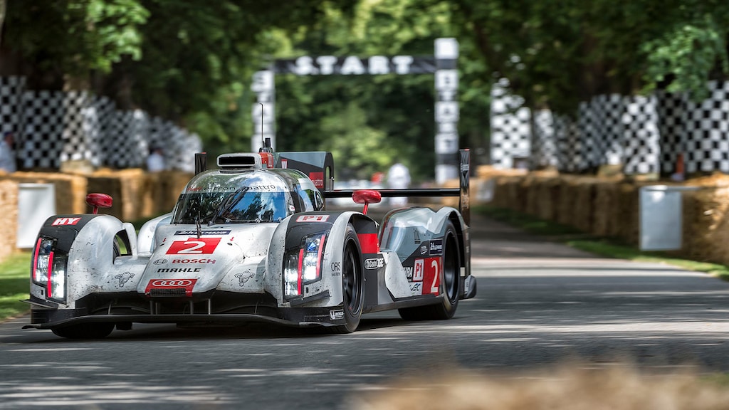 An Audi sports car drives towards the camera on a race track. An arch with the word ‘Start’ can be seen in the background.