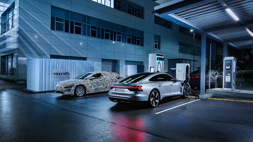 Several Audi models are parked at a charging station in front of a building