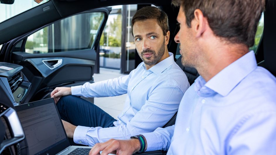 Two Audi employees are talking in a vehicle