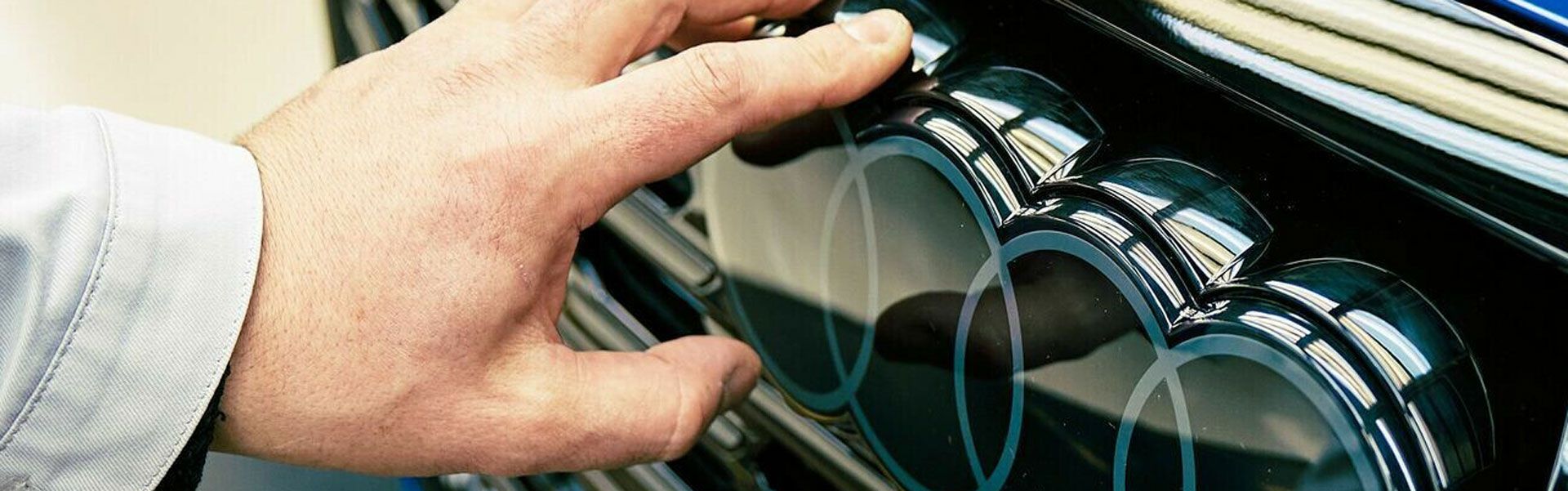 Hand berührt das Audi Logo an einem Fahrzeug