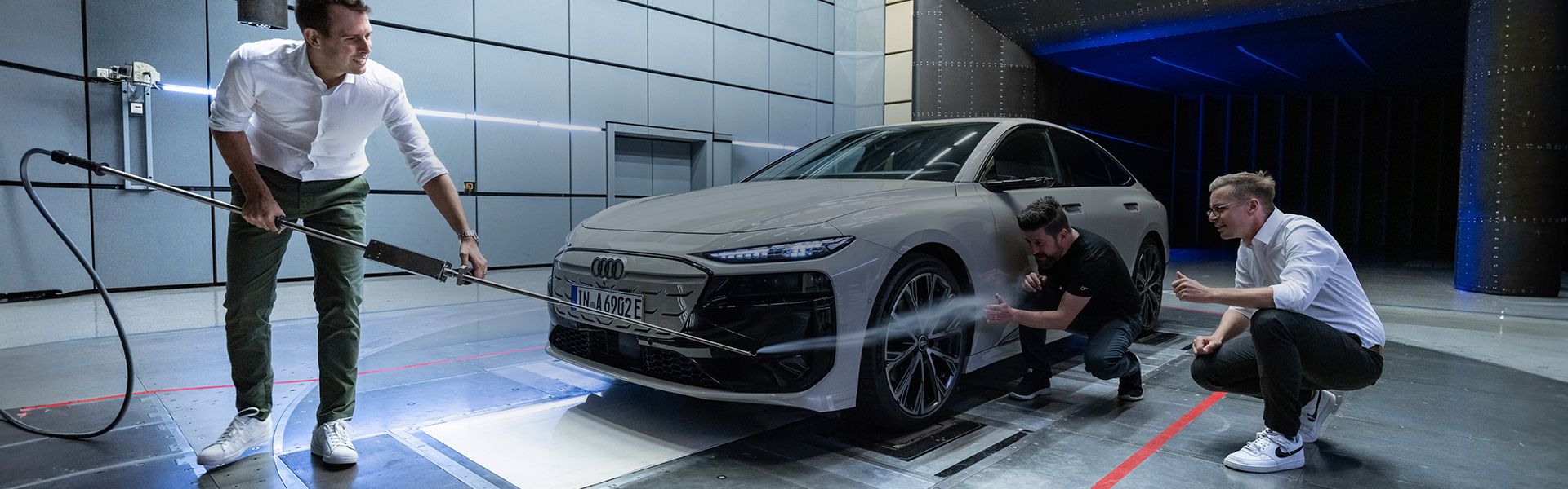 Drei Audi Ingenieure an einem weißen Audi A6 SPortback e-tron im Windkanal