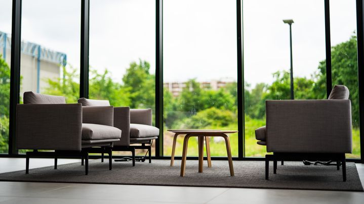 Sitzmöbel vor einer Fensterfront mit einem Ausblick ins Grüne