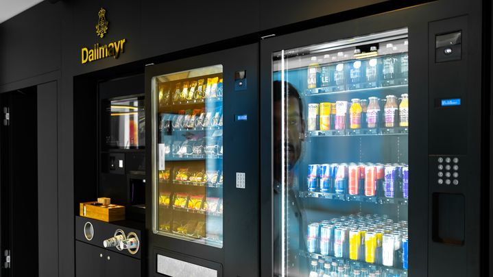 Ein schwarzer Automat mit Snacks und Drinks und dem goldenen Dallmayr Logo