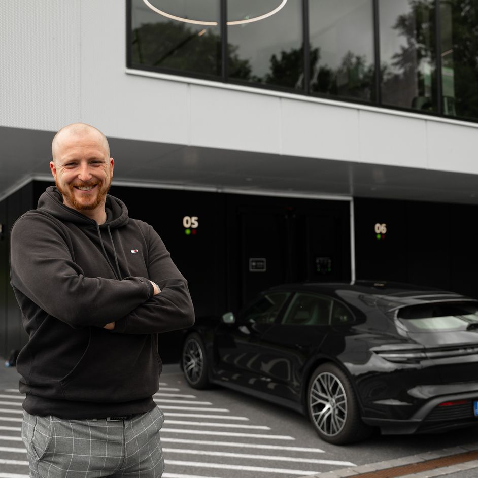 Dominik steht vor dem Audi charging hub und lächelt